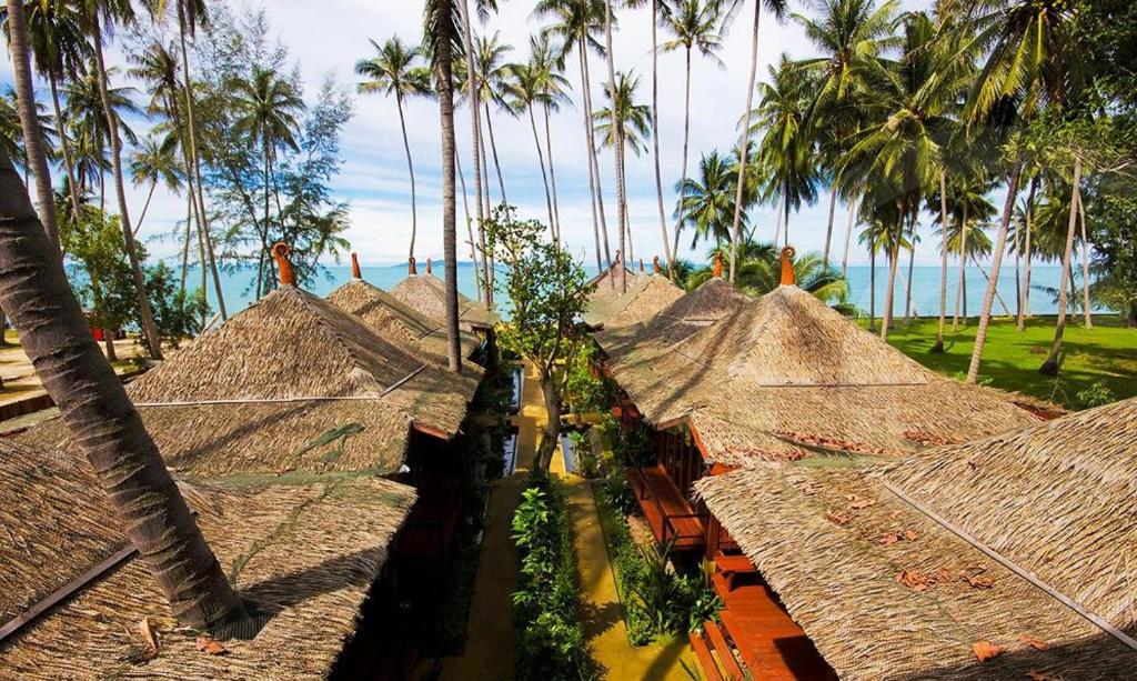 eine Gruppe von Strohhütten mit Palmen und dem Meer in der Unterkunft Lipa Bay Resort in Lipa Noi