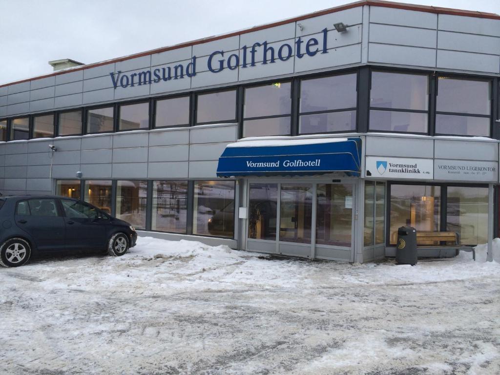 un'auto parcheggiata di fronte a un edificio nella neve di Vormsund Golf Hotell a Vormsund