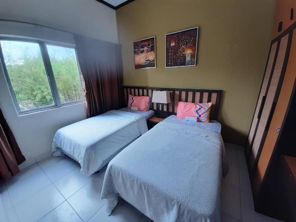 een kamer met 2 bedden en een raam bij Gold Coast Morib Resort Apartment Ezzy in Kampong Tanjong Pechah