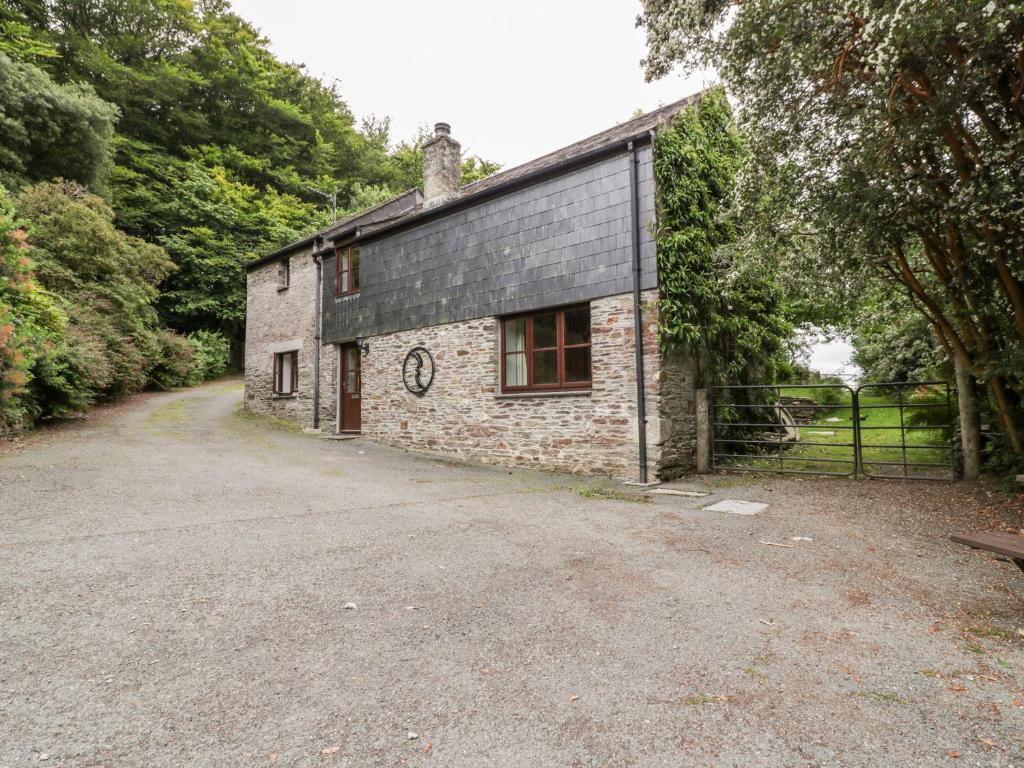 a stone house with a gravel driveway in front of it at Ribby Barn in Lostwithiel