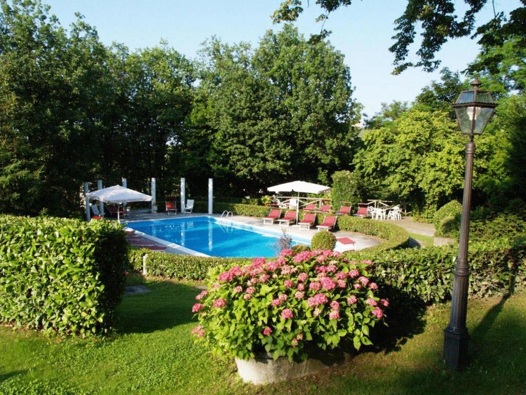a garden with a swimming pool and a street light and flowers at Park Hotel Fantoni in Tabiano