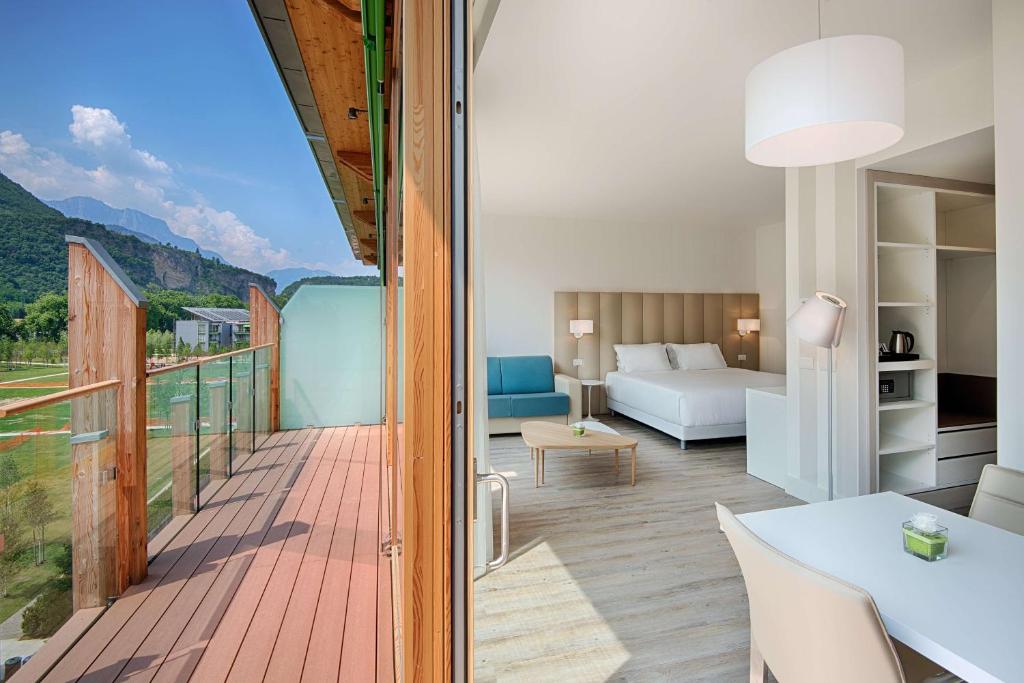 a room with a balcony with a table and a couch at NH Trento in Trento