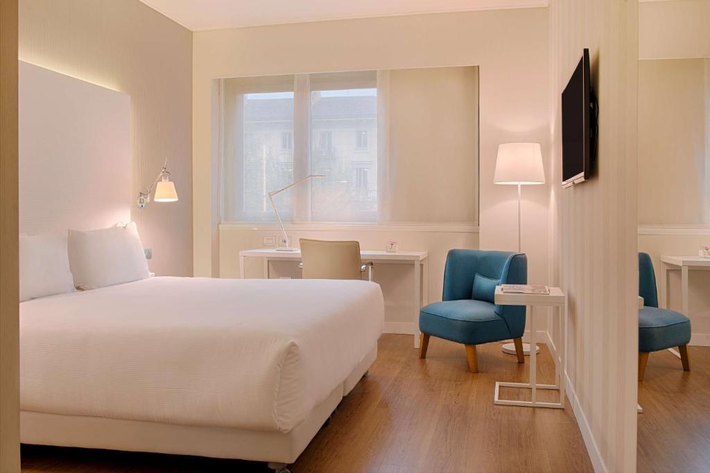 a hotel room with a bed and a desk and chair at NH Torino Centro in Turin