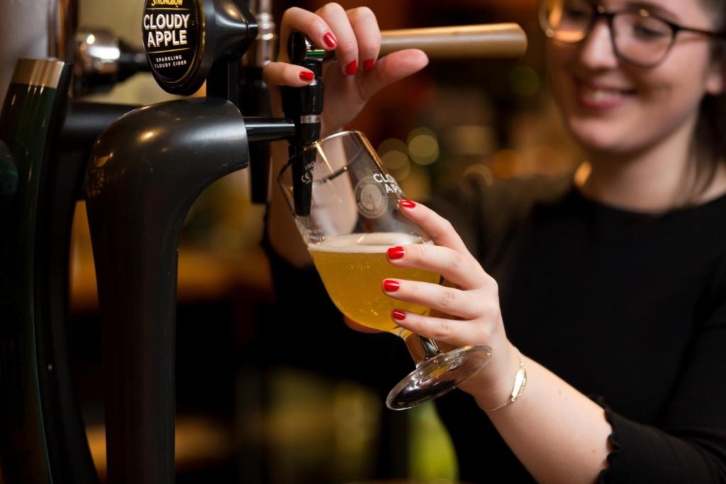a woman pouring a drink into a wine glass at Warkworth House Hotel in Warkworth