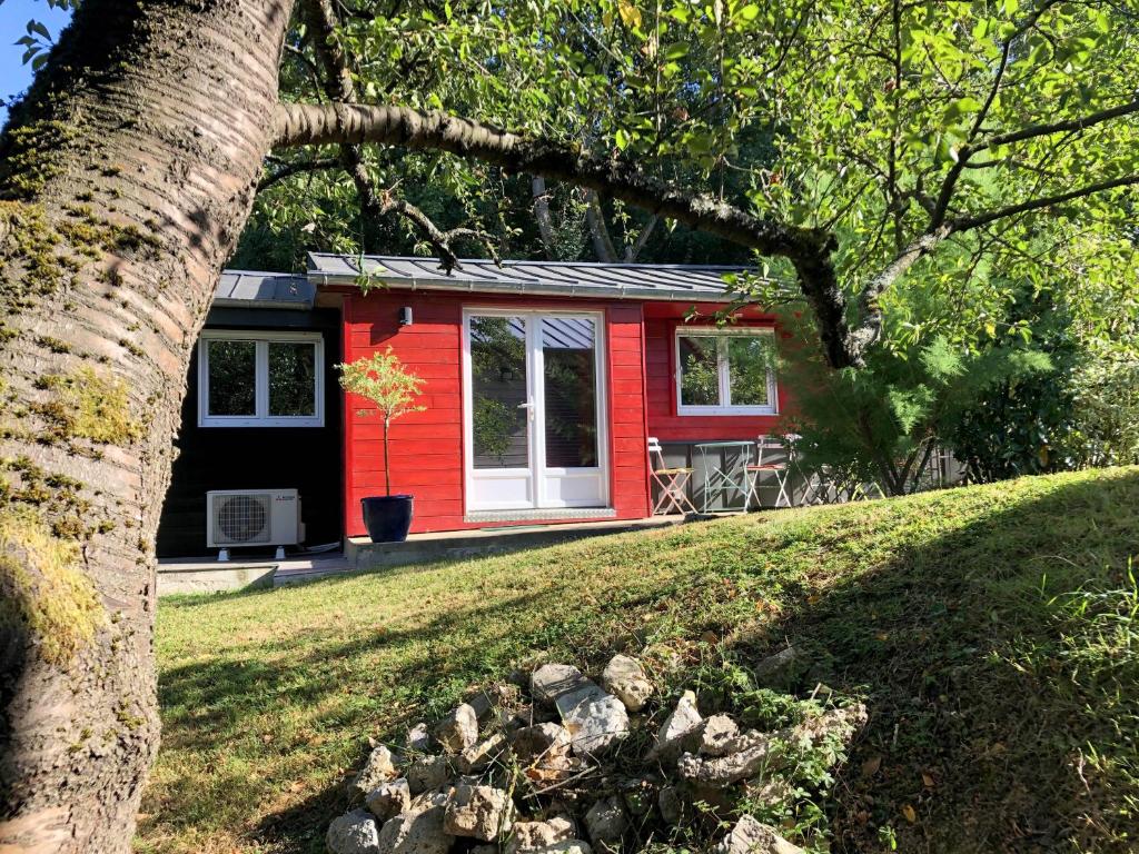 a red tiny house in a yard with a tree at Le Cabanon de Chessy in Chessy