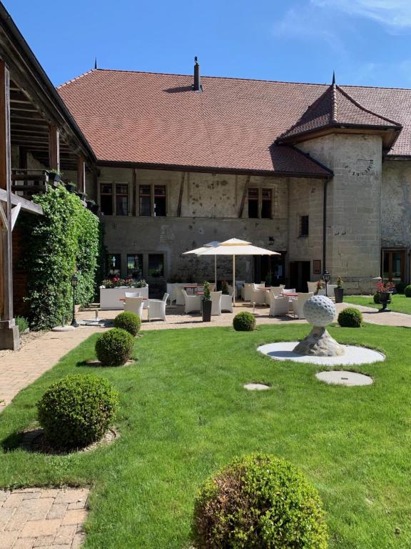 Le château de Vuissens في Vuissens: مبنى فيه ساحة فيها كراسي ومظلة