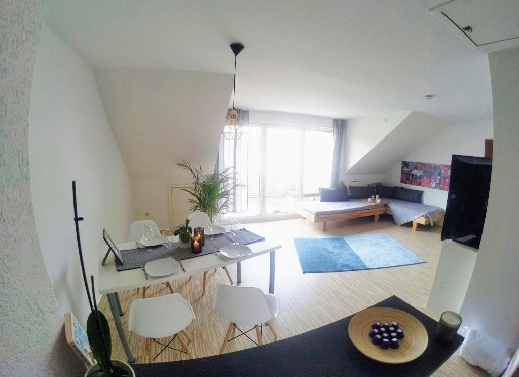 a living room with a table and white chairs at Über den Dächern von Kirchheim, Modernes Apartment in Kirchheim unter Teck