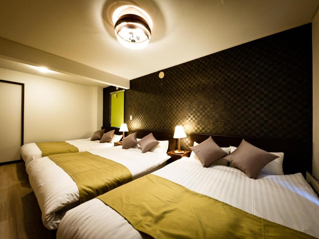 a hotel room with three beds in a room at Hongo Street House - Vacation STAY 8636 in Sapporo