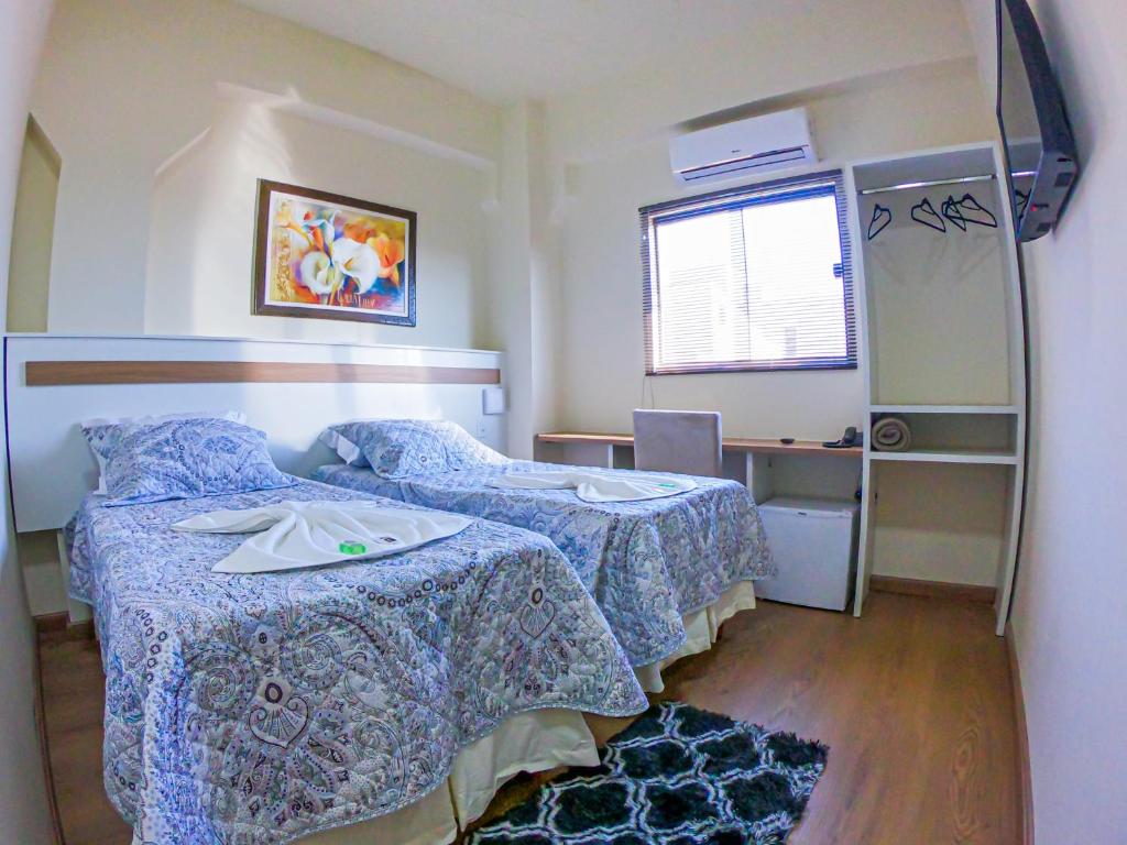 a bedroom with two beds and a desk and a window at HOTEL LAGO ARARAS in Araras