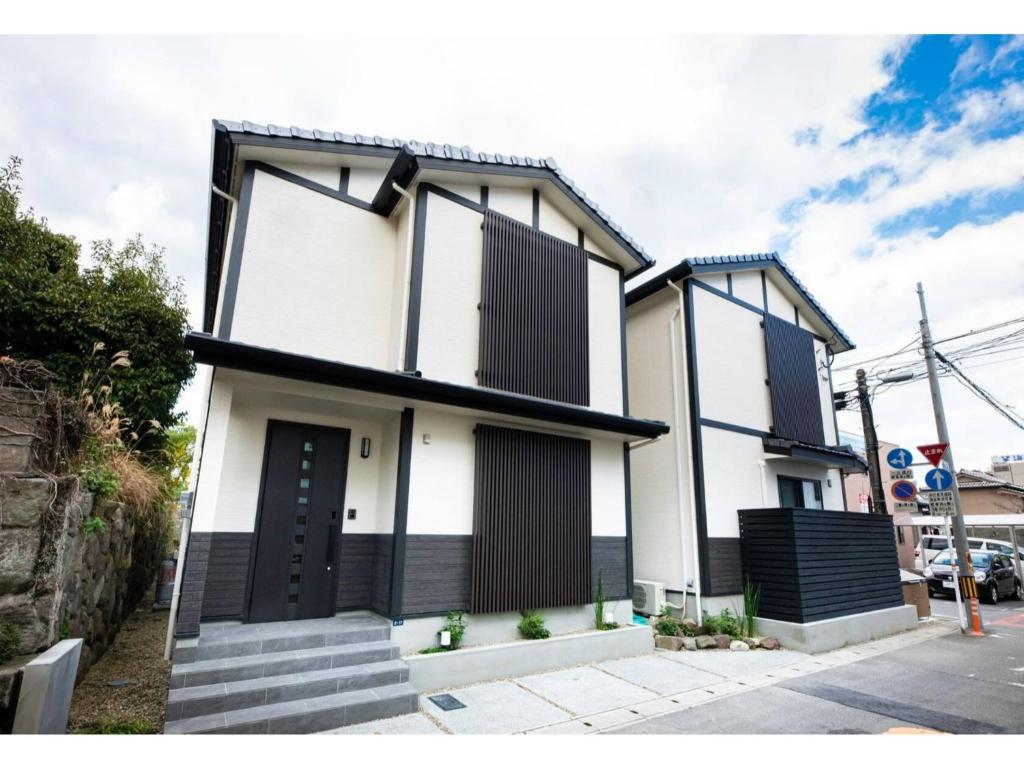 una casa blanca con una puerta negra en una calle en BEPPU NO YU SORA - Vacation STAY 87966 en Beppu