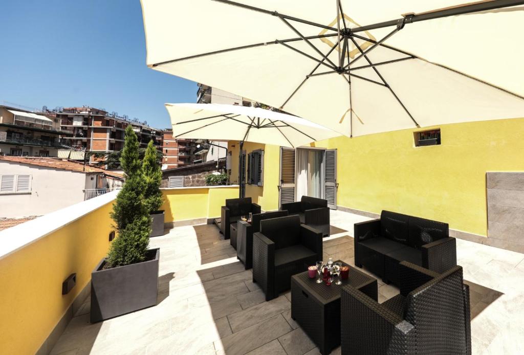 um pátio no último piso com cadeiras pretas e um guarda-sol em Carpe Diem Rooms em Castellammare di Stabia