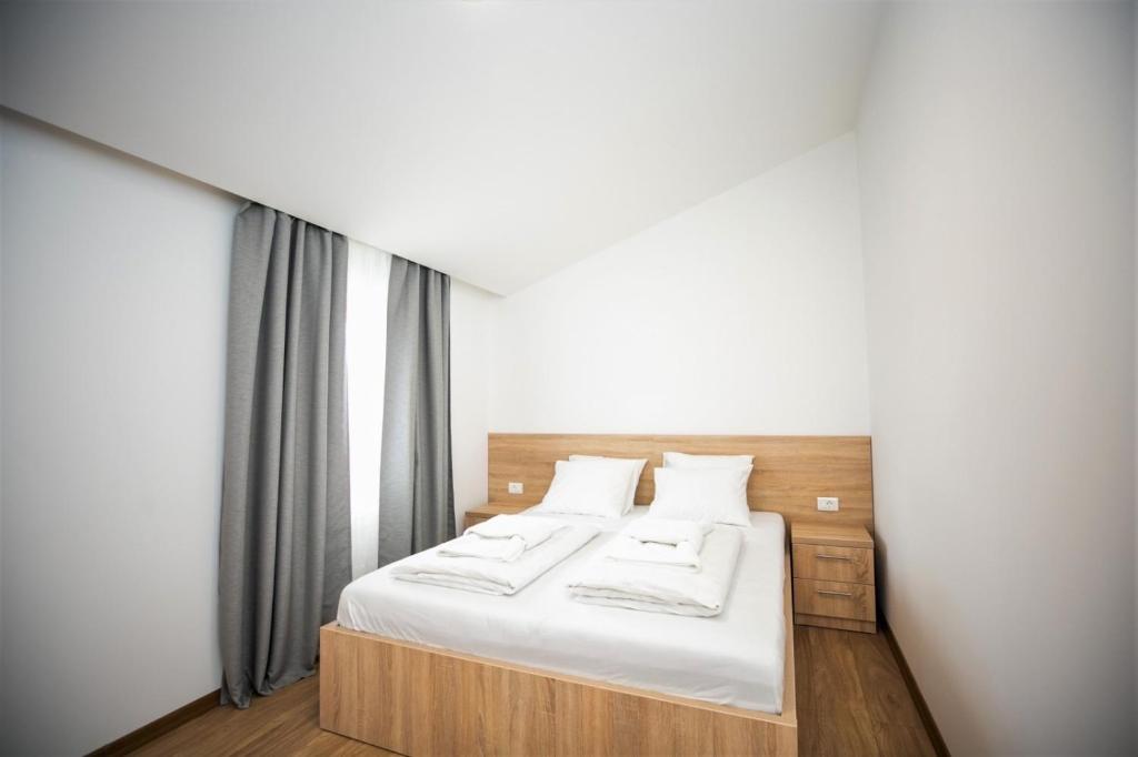 Schlafzimmer mit einem Bett mit weißer Bettwäsche und Kissen in der Unterkunft APARTMANI M&J Međugorje in Međugorje