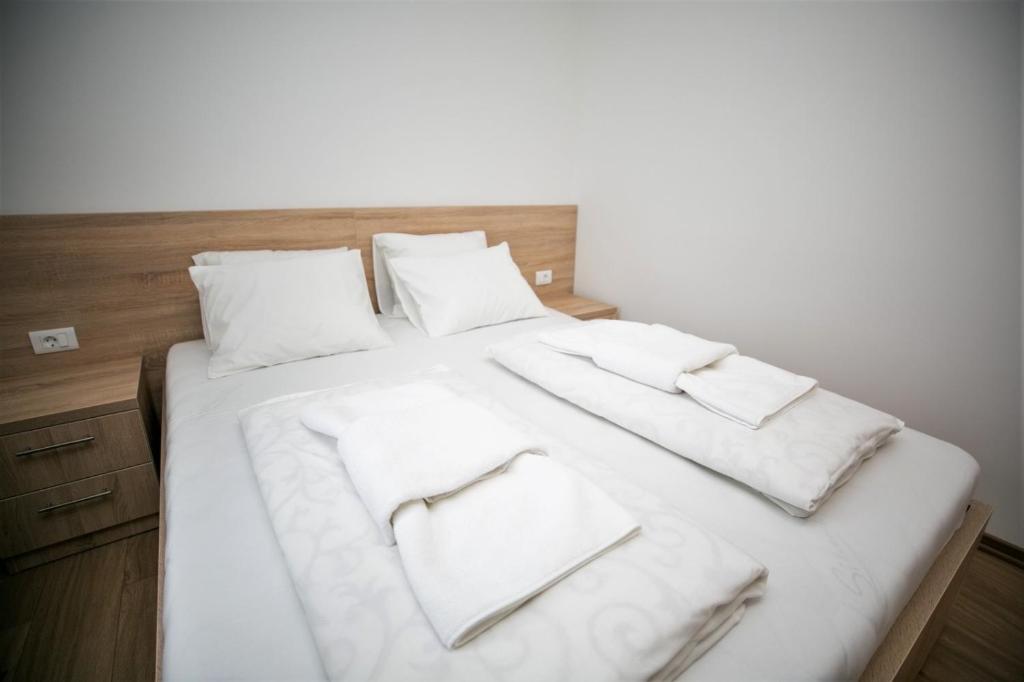 a bed with white blankets and pillows on it at APARTMANI M&amp;J Međugorje in Međugorje