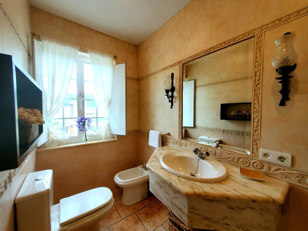 a bathroom with a sink and a toilet and a mirror at Apartamentos Turísticos Rosa in Ribadeo