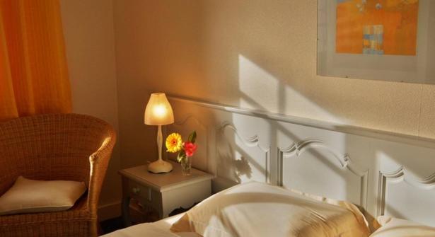 a bedroom with a bed and a chair and a lamp at Chambres d'Hôtes Ferme de Kereven in Clohars-Fouesnant