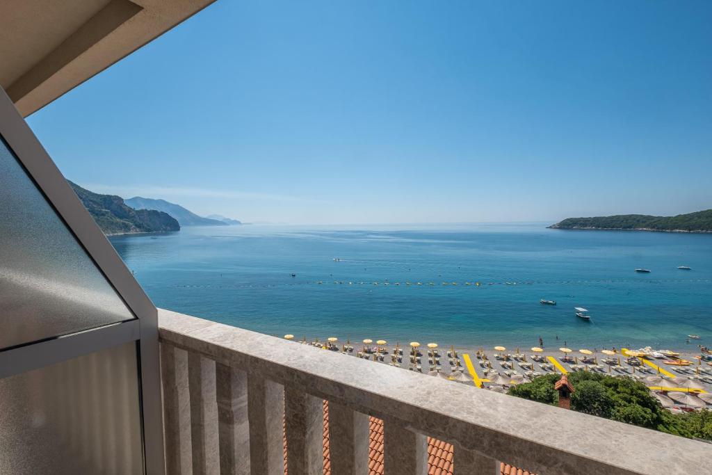 a balcony with a view of a beach and the ocean at Poseidon The Beach Hotel in Budva