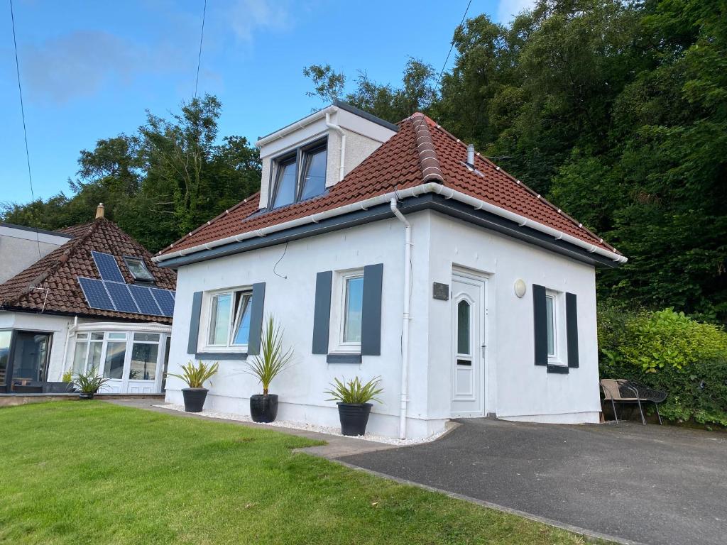 a white house with potted plants in a yard at The Wee Cottage by the Ferry in Gourock