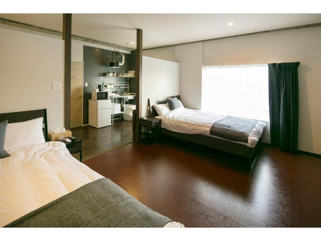 a bedroom with two beds and a large window at ROI SPACE KAGOSHIMA - Vacation STAY 87819 in Kagoshima