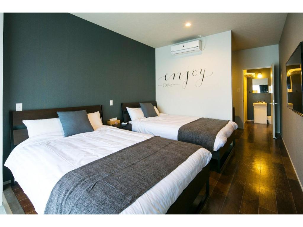 twee bedden in een hotelkamer met een kamer met twee bij ROI SPACE KAGOSHIMA - Vacation STAY 87752 in Kagoshima