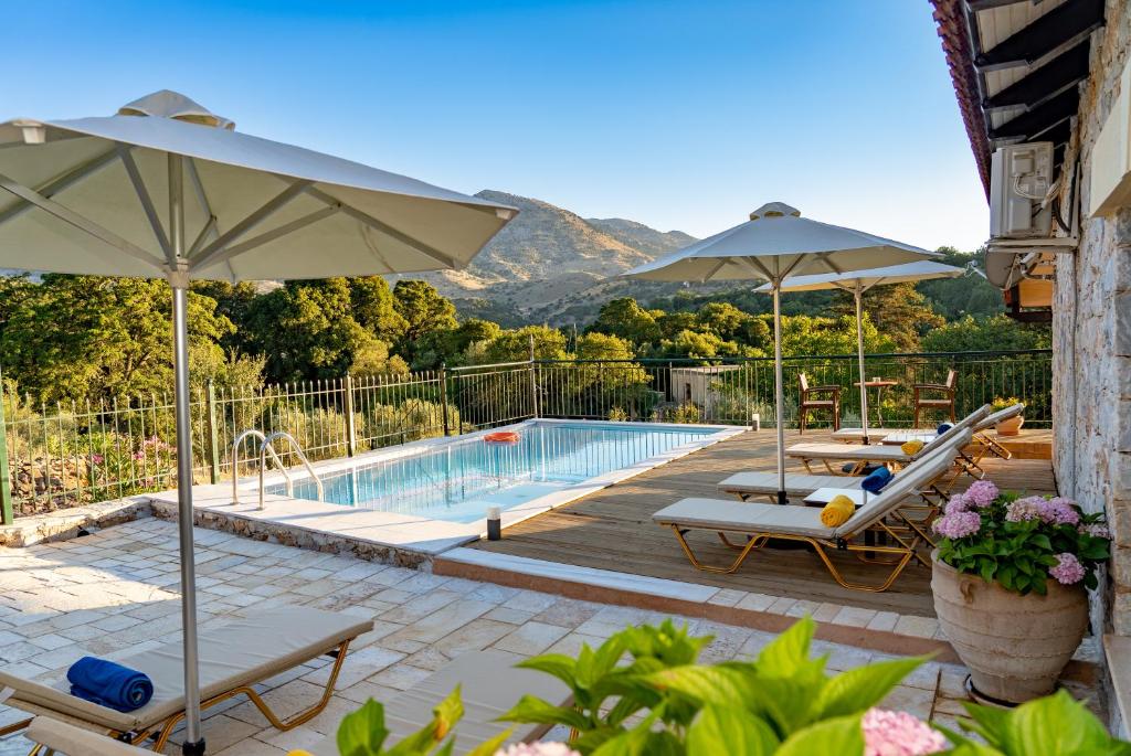 una piscina con sillas y sombrillas y una piscina en Villa Kleio, en Kámboi