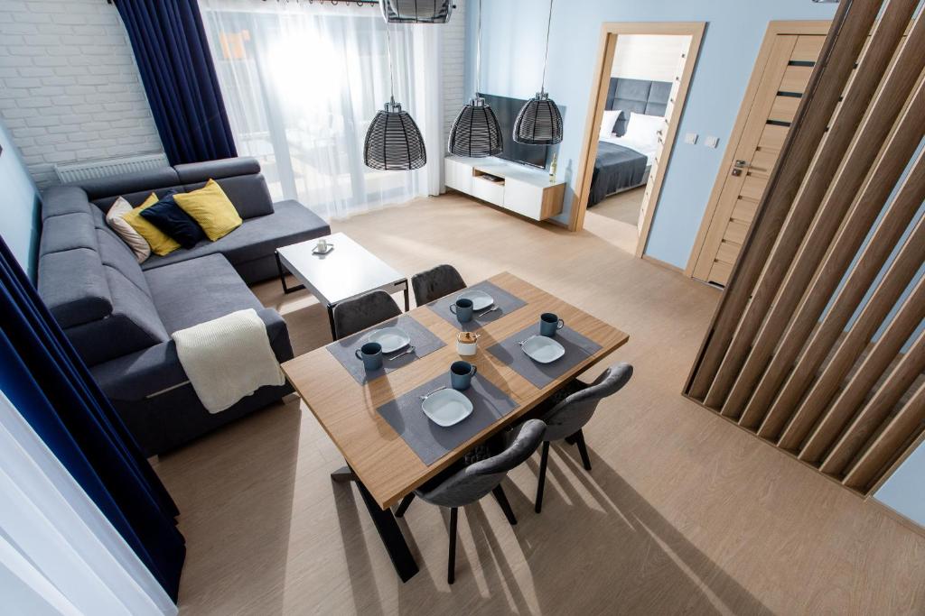 a living room with a table and a couch at Apartament SŁONECZNY 7 Dziwnów Gardenia z widokiem na morze EPapartamenty in Dziwnów Górny