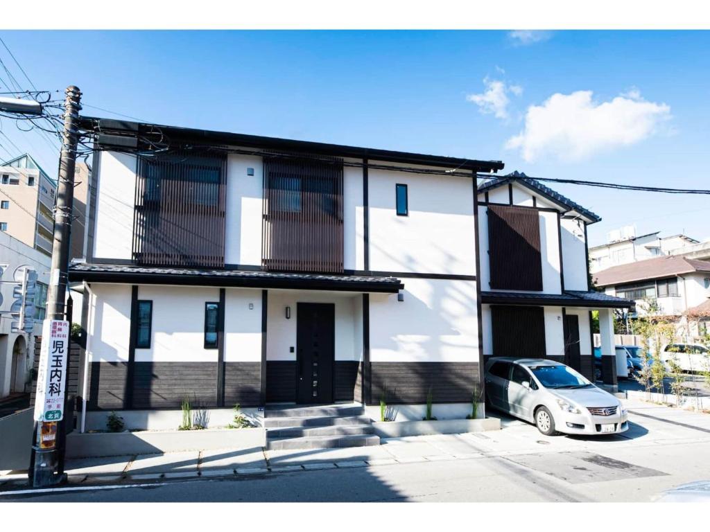 uma casa branca com um carro estacionado em frente dela em BEPPU NO YU TSUKI - Vacation STAY 87965 em Beppu