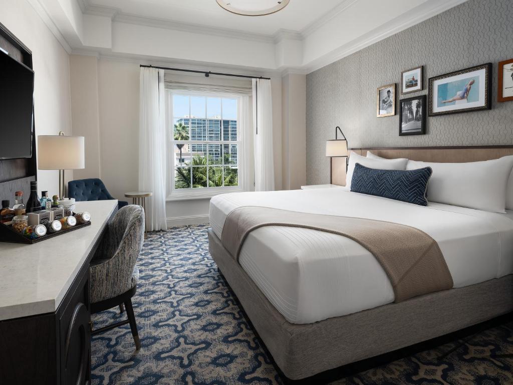 a hotel room with a large bed and a desk at La Valencia Hotel in San Diego