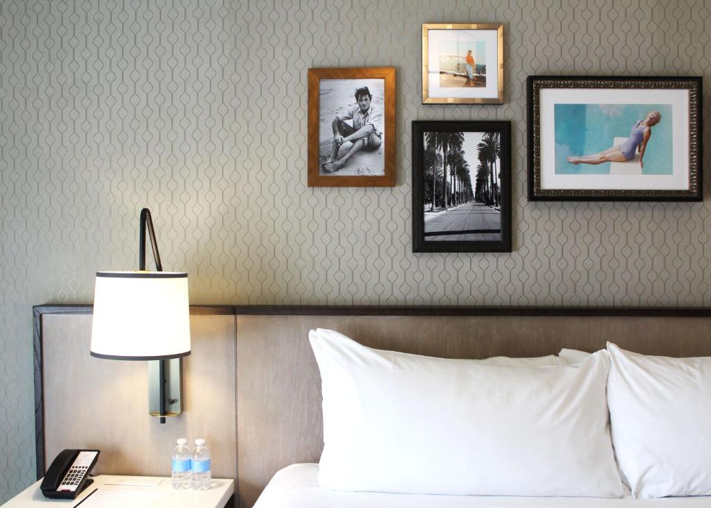 a bedroom with a bed with pictures on the wall at La Valencia Hotel in San Diego