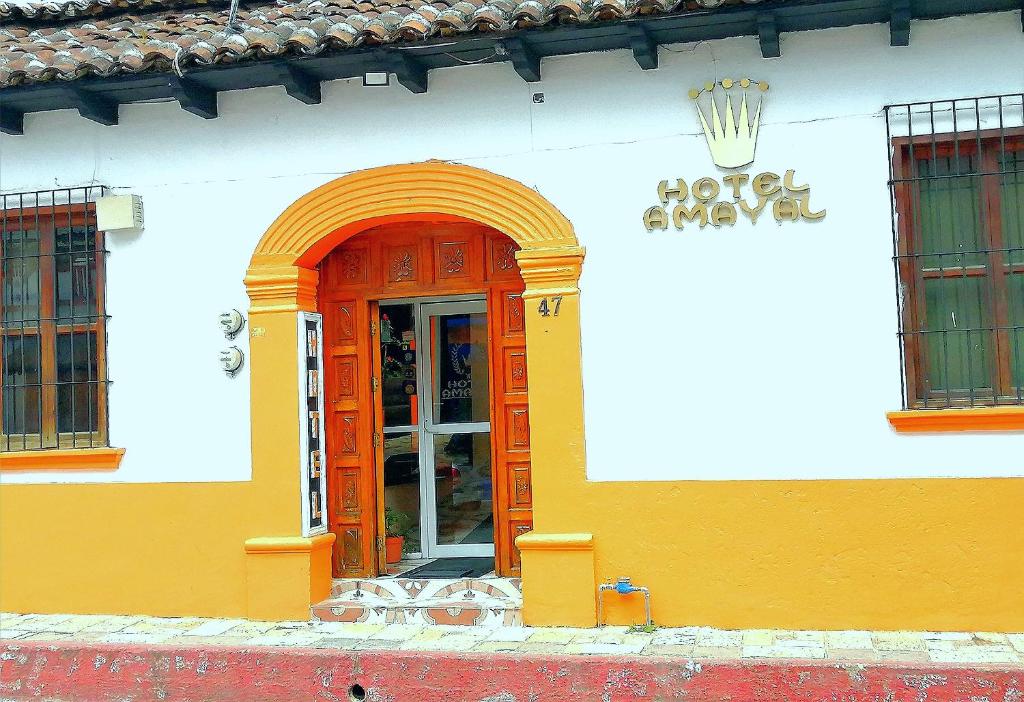 a yellow and white building with an orange door at Hotel Amayal in San Cristóbal de Las Casas