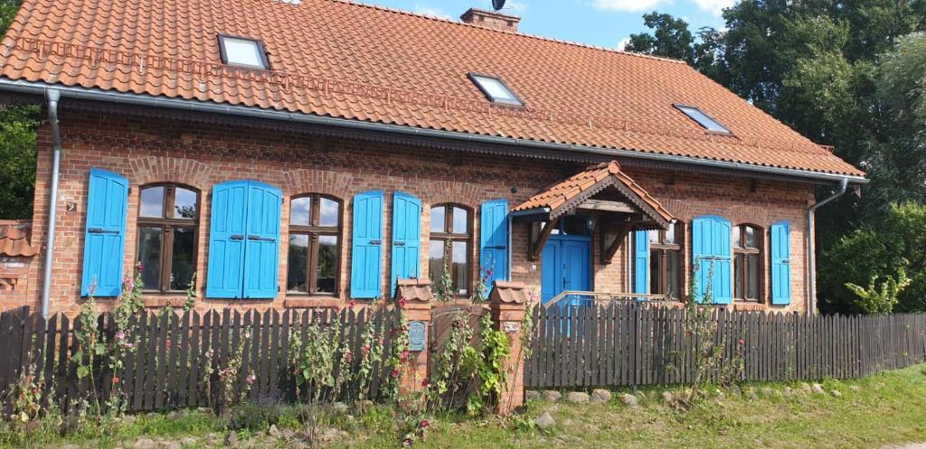 a brick house with blue windows and a fence at Dom Mazurski Mącze in Ełk