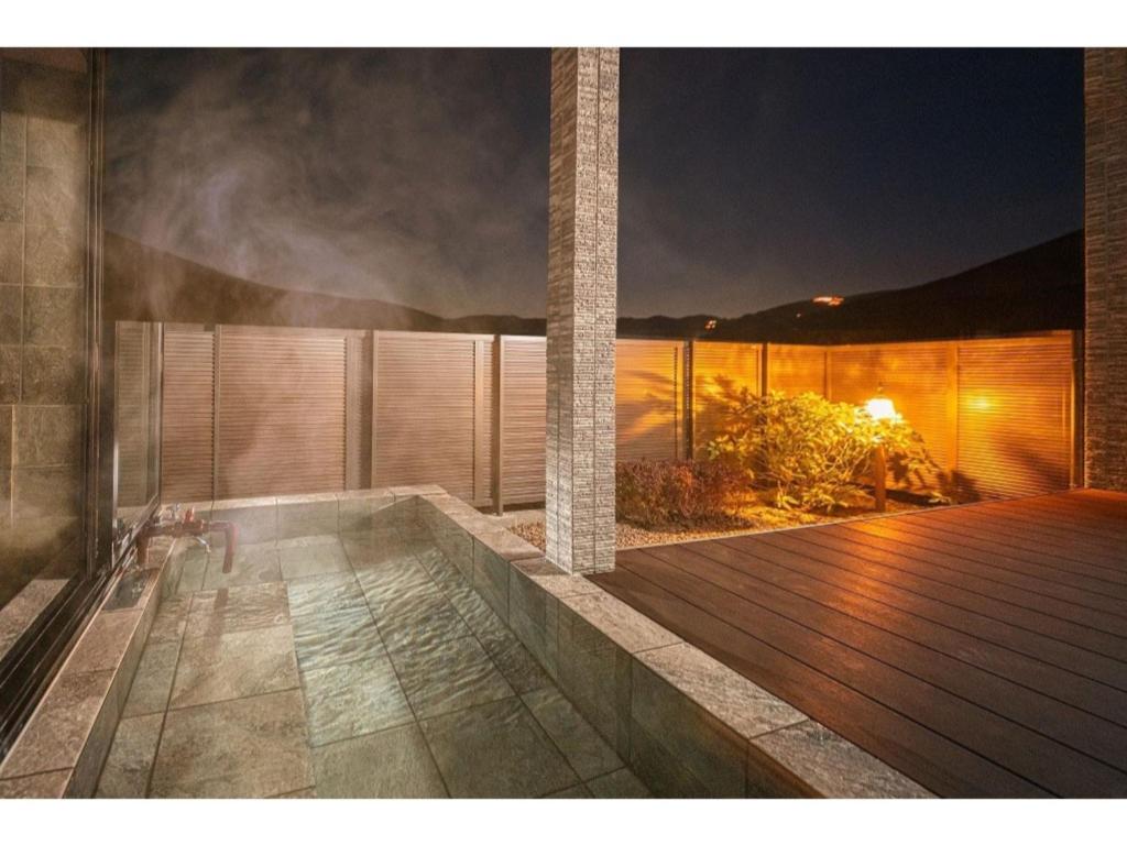 una casa con bañera de hidromasaje en una terraza por la noche en YUHUROTEN YOJYOU NO BI - Vacation STAY 87032, en Yufu
