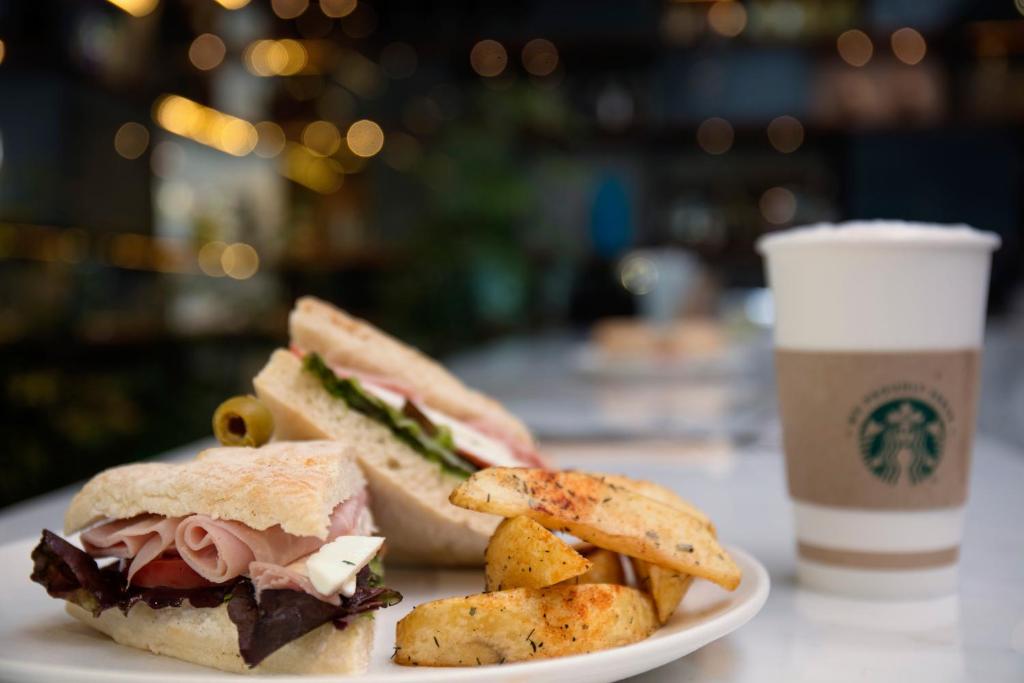 A café-style sandwich and potato wedges served with a takeaway coffee.