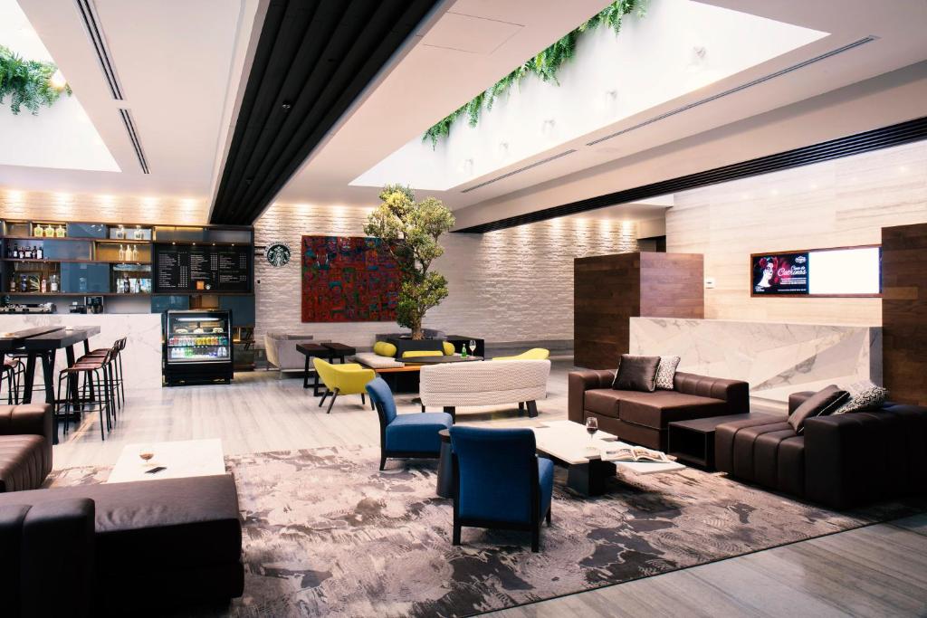 A contemporary lobby lounge with varied seating, a bar counter and a wall-mounted television.