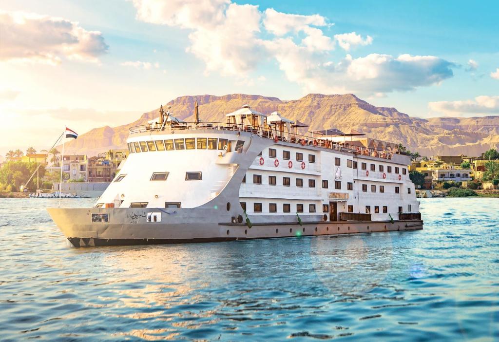 ein Kreuzfahrtschiff im Wasser mit Bergen im Hintergrund in der Unterkunft Champollion II 5 Stars Nile cruise in Luxor