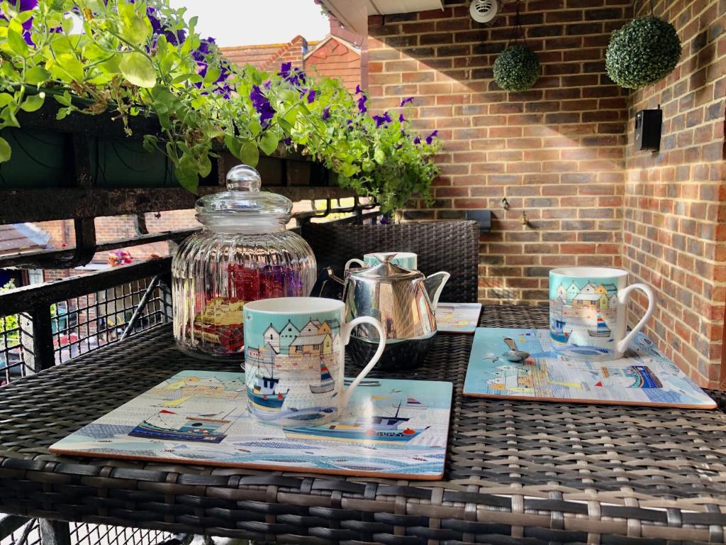 Una mesa con un jarrón y dos tazas. en St Georges Balcony Suite en Portsmouth