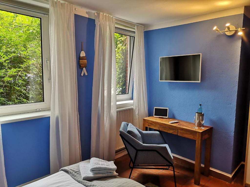 a bedroom with a desk and a tv on a blue wall at Liebevoll hinterm Deich in Lehe