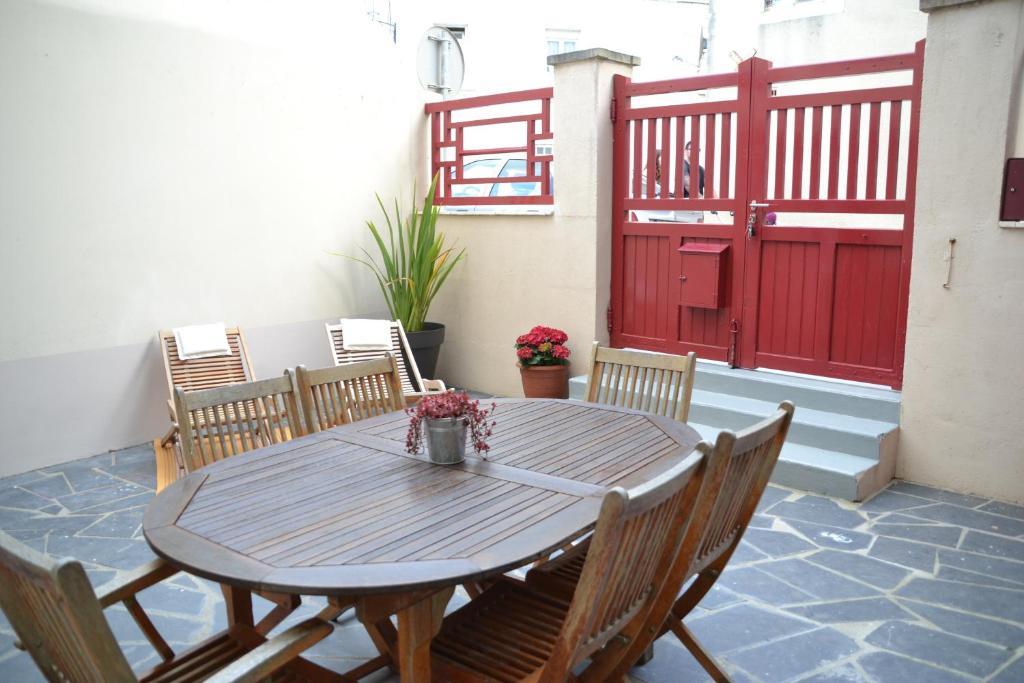 a wooden table and chairs on a patio with a red door at La Noroît du port in Port-en-Bessin-Huppain