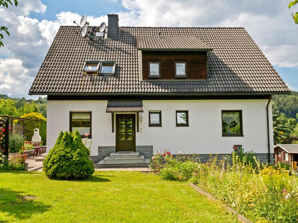 a white house with a black roof at Apartment with garden view in the Erzgebirge in Pöhla