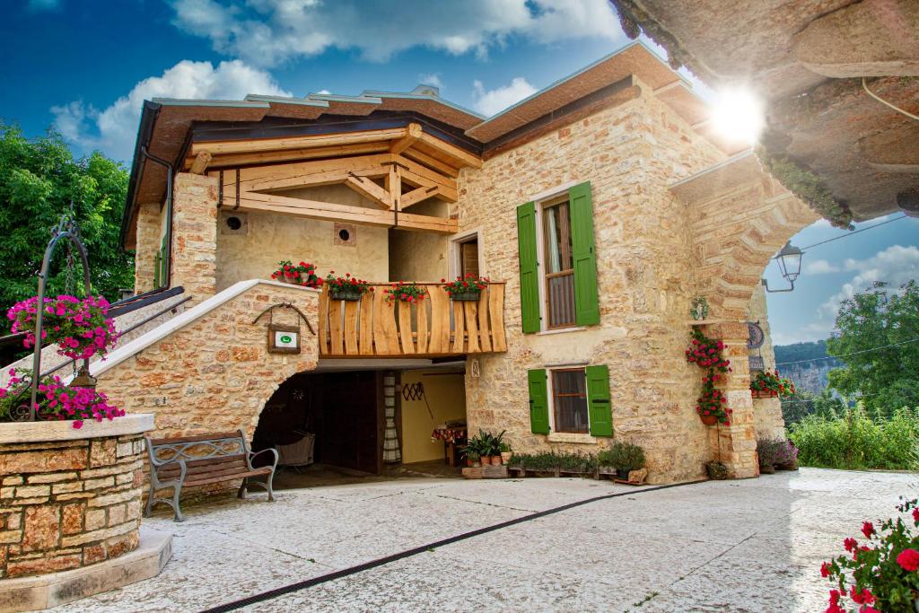 a stone house with a balcony and a bench at b&b le nosare in Bosco Chiesanuova