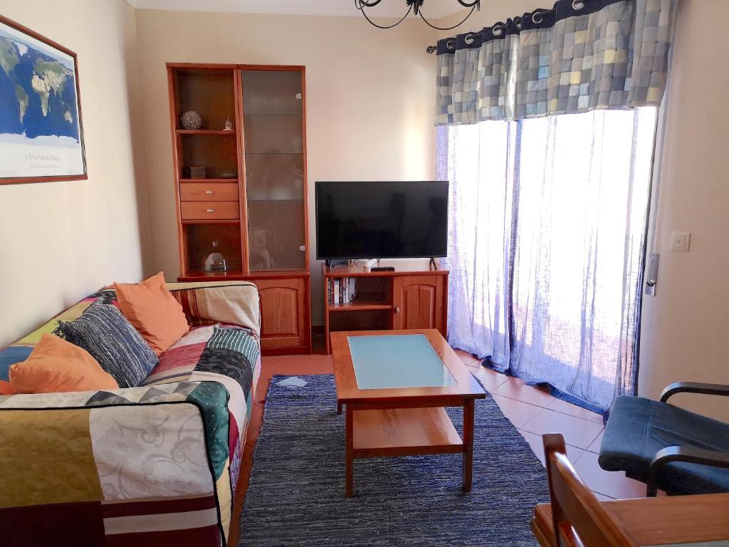 a living room with a couch and a flat screen tv at Home By The Sea in Sesimbra