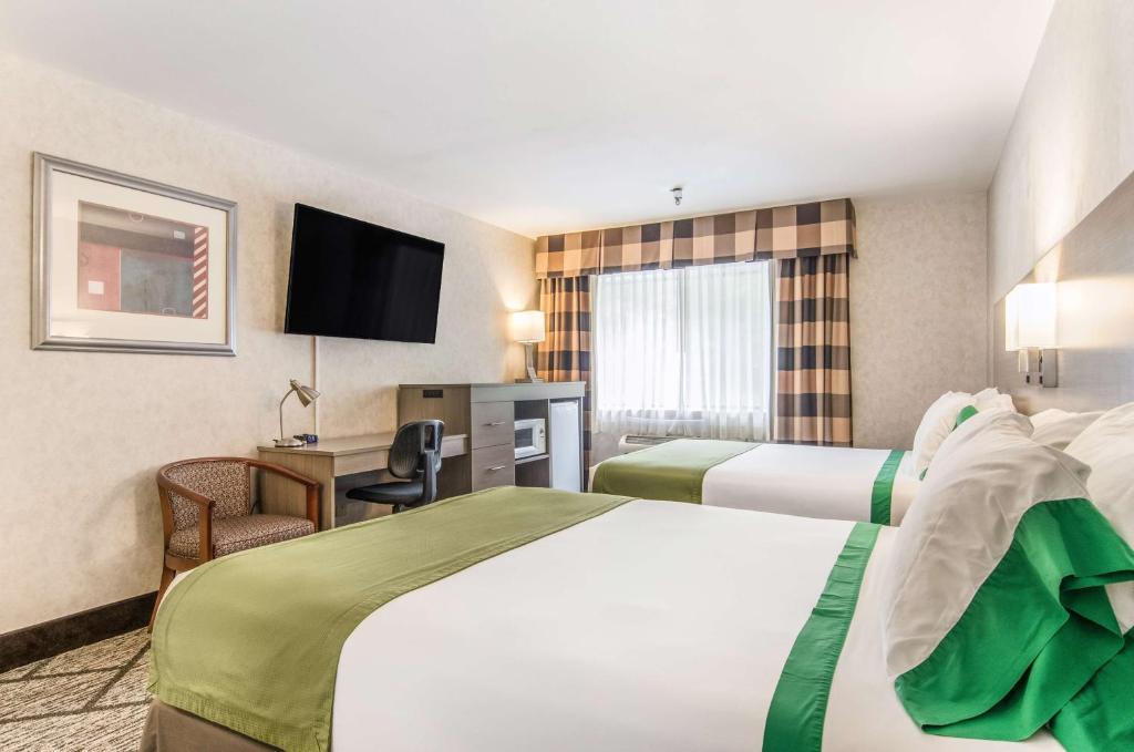 Habitación de hotel con 2 camas y TV de pantalla plana. en GuestHouse Inn & Suites Poulsbo, en Poulsbo