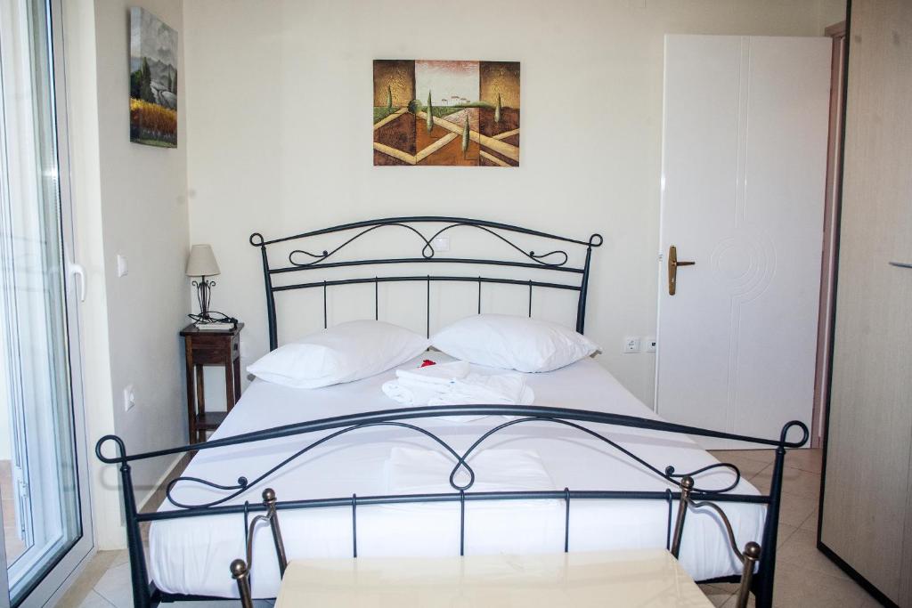 Bett mit weißer Bettwäsche und Kissen in einem Zimmer in der Unterkunft Maria Apartments in Lefkada Town