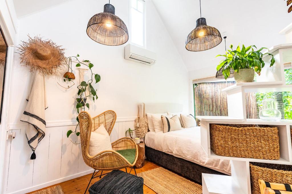 a bedroom with a bed and two chairs and potted plants at Boho Hill Waiheke Island in Palm Beach