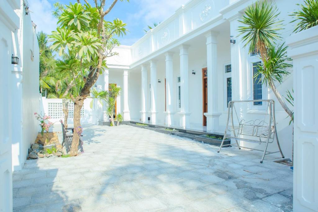 ein weißes Gebäude mit Palmen im Innenhof in der Unterkunft Lavender Tan Thanh Hotel mini resort in Cong Thanh (3)