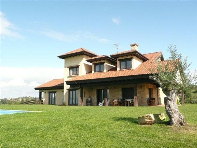 a large house with a tree in the yard at La Casa de Orviz in Siero