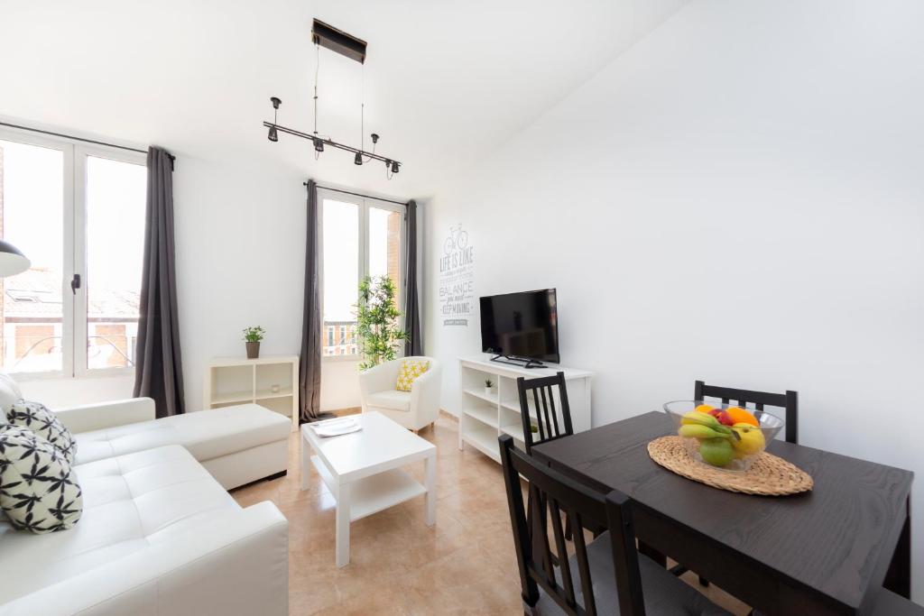 a living room with a table and a white couch at Boutique Apartments in the Heart of Madrid in Madrid