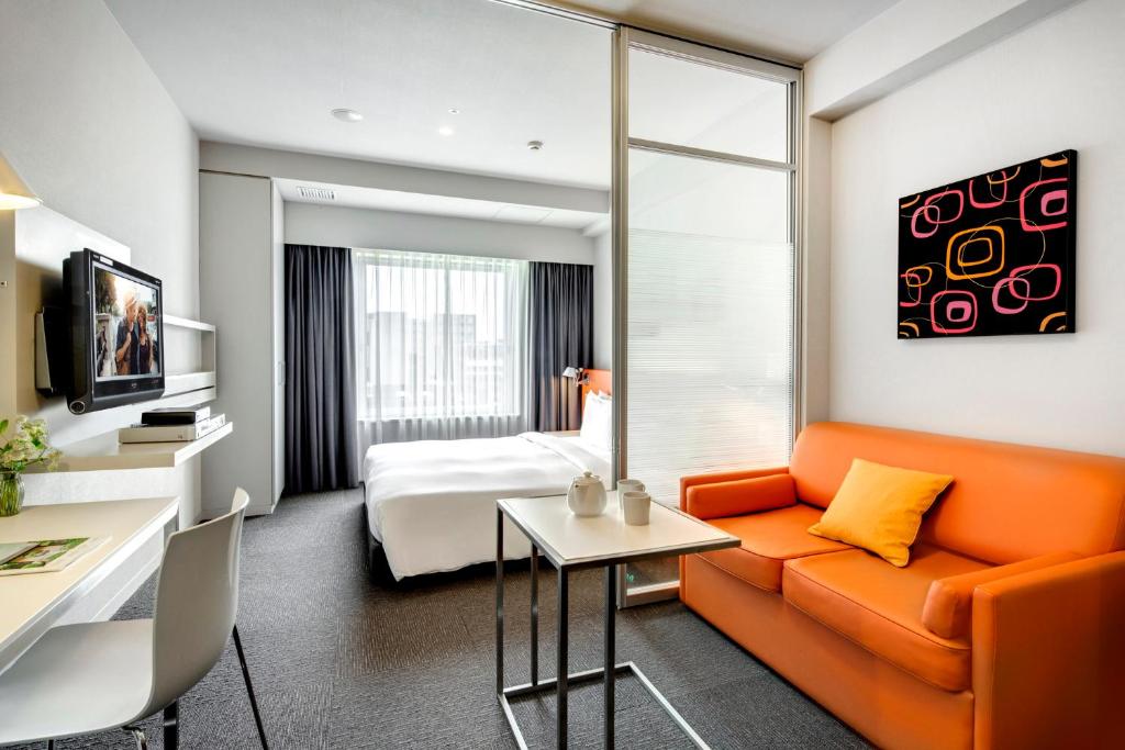 a hotel room with an orange couch and a bed at Citadines Shinjuku Tokyo in Tokyo