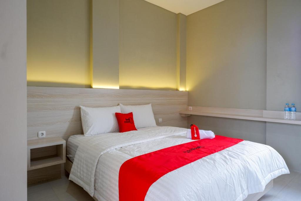a bedroom with a large bed with red pillows at RedDoorz Syariah near PRPP Semarang in Kalibanteng-lor
