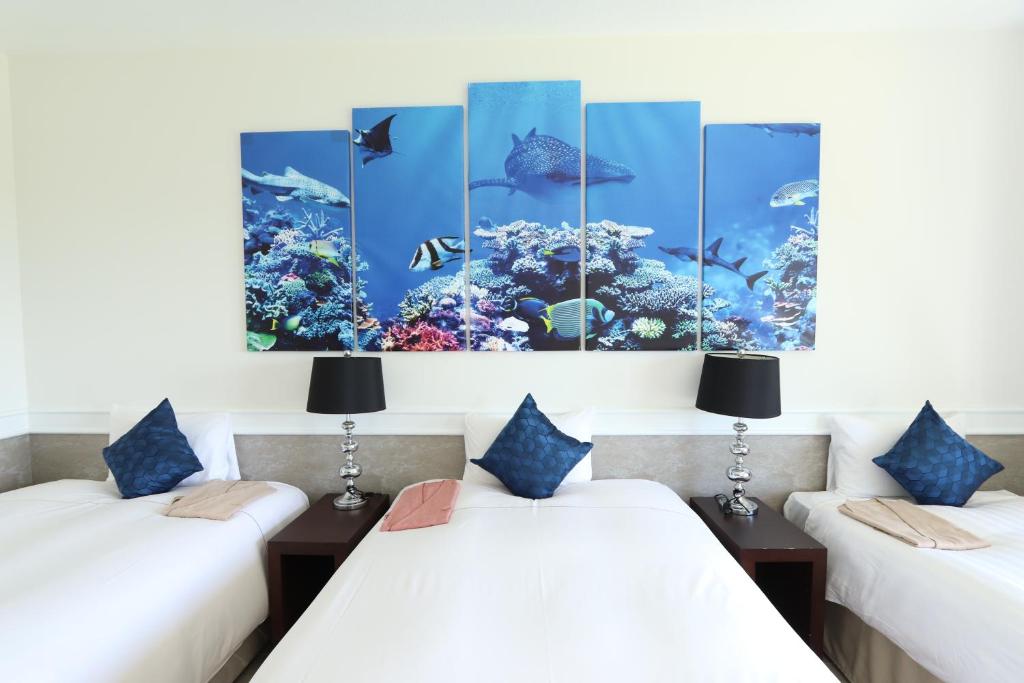 a room with two beds and an aquarium painting on the wall at Royal View Hotel Churaumi in Motobu