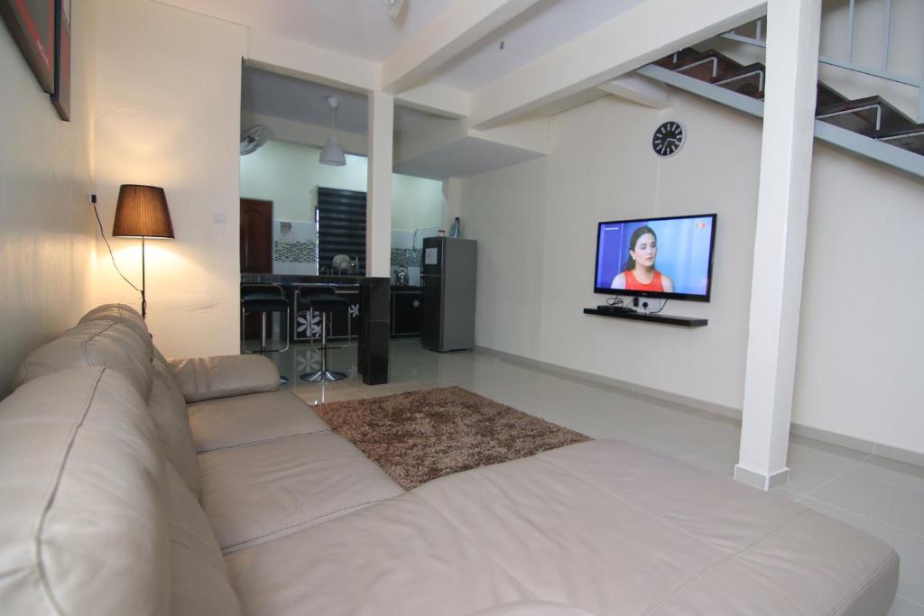 sala de estar con sofá y TV en la pared en Homestay Hj Esmon 3 UTHM Parit Raja, en Parit Raja